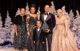 Jeremy Anderson, Man of the Year award recipient, posing with his wife and kids at the STEMii Awards captured by Omni Worldwide event photography.